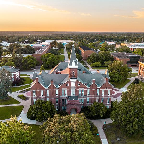 Aerial view looking over Old Main with a sunset in the background.